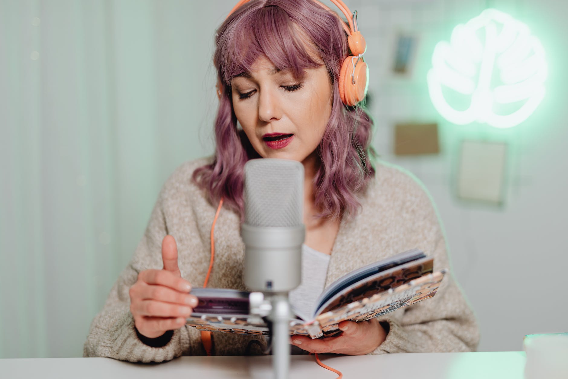 a woman talking on a microphone while reading a book